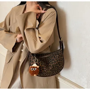 Leopard-Canvas-Tasche mit Lederriemen und Plüsch-Anhänger getragen zu einem Trenchcoat