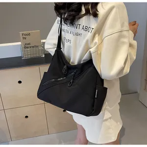 Detail of black nylon tote bag featuring diagonal zip pocket and brand side label