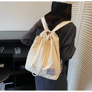 Dettaglio dello zaino in nylon bianco crema con coulisse e toppa con logo in primo piano