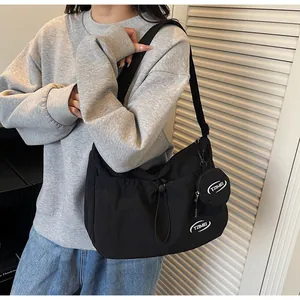 Detail of a black nylon crossbody bag with a round charm pouch and TZIMEI logo