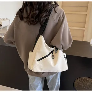 Detail view of large cream crossbody bag featuring black zipper and adjustable strap