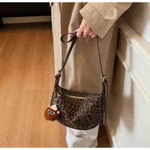 Detailansicht der Halbmond-Tasche mit Leopardenmuster, Plüsch-Anhänger und Gold-Details