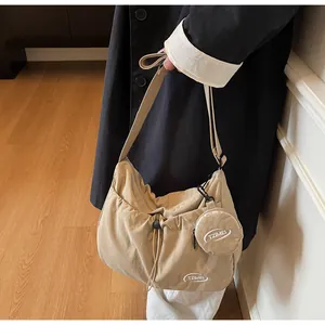 Close-up of a khaki nylon crossbody bag with drawstring detail and round coin pouch