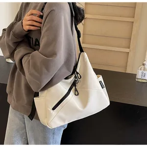 Detail view of white minimalist crossbody bag with black wide strap and zipper accents