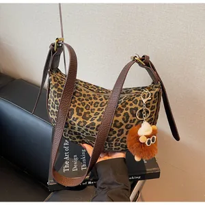Detail der Canvas-Tasche mit Leopardenmuster, braunem Lederriemen und Plüsch-Anhänger