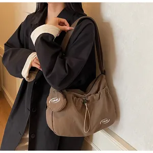 Detail of minimalist dark brown nylon crossbody bag with small round pouch and logo