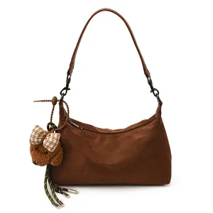 Brown suede half-moon shoulder bag with a dark leather strap and dog plush charm