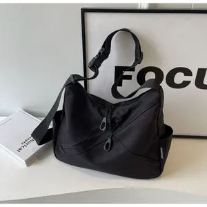 Close-up of black commuter crossbody bag with dual diagonal zippers and wide strap