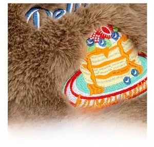 Gros plan détaillé du tissu en peluche marron avec broderie colorée et texture douce