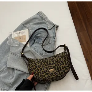 Detail der Canvas-Tasche mit Leopardenmuster, handgefertigtem Metall-Logo und Lederriemen
