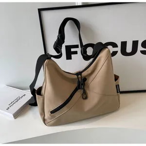 Macro shot of khaki nylon crossbody bag featuring black zipper and brand woven label