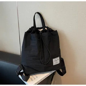 Dettaglio dello zaino in nylon nero impermeabile con chiusura a coulisse ed etichetta bianca