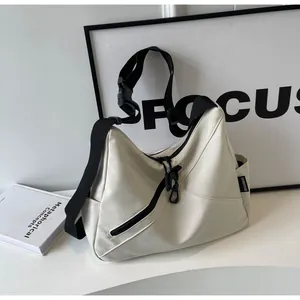 Detail of off-white waterproof nylon crossbody bag with wide black strap and front zipper pocket