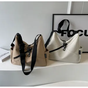 Detail view of khaki and beige nylon tote bags with wide black straps and buckle details
