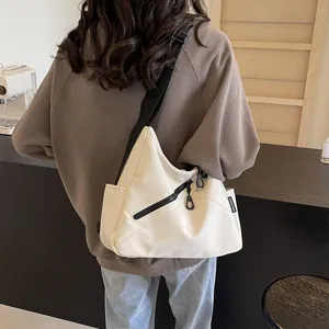 Off-white nylon crossbody tote bag with wide black strap shown on a person