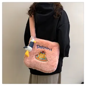 Détail d'un sac bandoulière en peluche rose avec broderie gâteau et canard