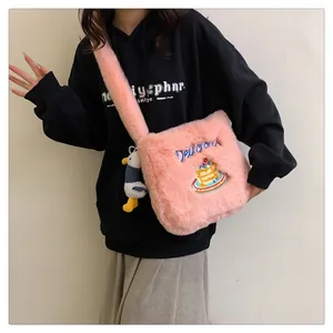 Gros plan sur le sac en peluche rose avec broderie Delicious et breloque canard mignon
