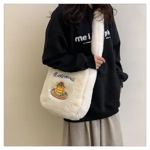 Détail d'un sac bandoulière en peluche blanche avec broderie gâteau colorée