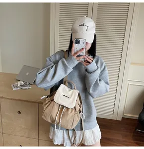 Dettaglio dello zaino in nylon beige con chiusura a coulisse e logo del marchio inciso