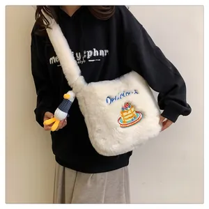 Gros plan d'un sac bandoulière en peluche blanche avec broderie et charme canard