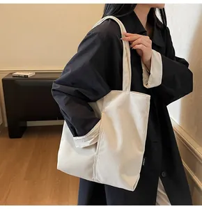 Detail of white corduroy tote bag featuring a side pocket and minimalist logo tag