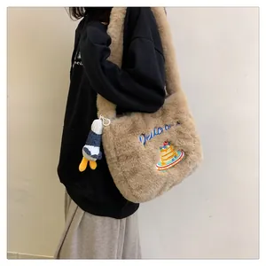 Détail du sac à bandoulière en peluche kaki avec broderie gâteau et pendentif canard
