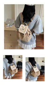Dettaglio della chiusura a coulisse e del ricamo sullo zaino leggero color beige