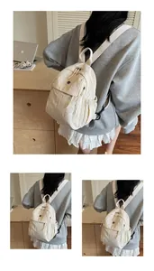 Détail du sac à dos en nylon crème avec poche frontale à rabat et poches latérales élastiques