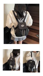Dettaglio mini zaino in nylon nero con chiusura a coulisse e logo sulla patta