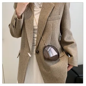 Model wearing a dark brown acrylic shell bag with gold chain strap over a brown blazer