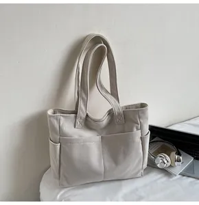 Detailed shot of beige corduroy tote bag showing textured fabric and front outer pockets