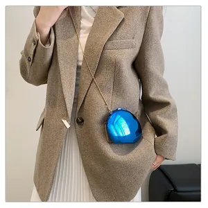 On-model view of a mini electric blue pebble crossbody bag with a gold chain strap