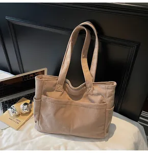 Detail showing the corduroy texture and multiple functional pockets on this khaki tote bag