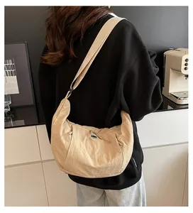 Detail of minimalist beige half-moon crossbody bag in lightweight textured fabric