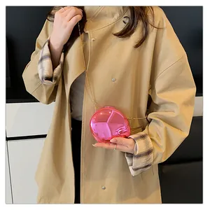 Close-up of pink sphere bag with metallic mirror finish and golden chain on beige coat