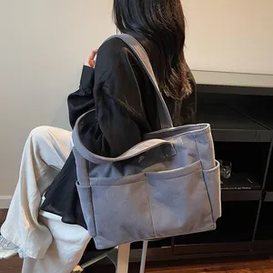 Large blue corduroy tote bag for women with two front pockets shown from a side view