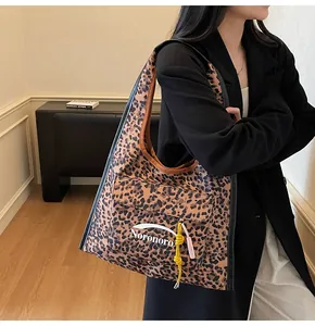 Detail of leopard print tote bag featuring a front pocket and pink tassel charm