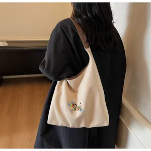 Detail of colorful donkey embroidery on cream canvas tote with brown shoulder strap