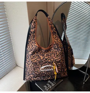 Close-up of leopard print canvas tote bag with pink tassel and front pocket detail