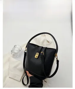 Detail of black lychee grain bucket bag with gold twist-lock and shoulder strap