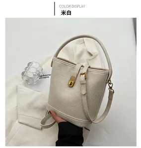 Detail view of cream white bucket bag with cracked texture faux leather and gold hardware