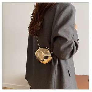 Detailed view of a gold spherical metal clutch bag with unique liquid metal structure