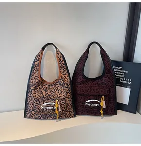 Detail of leopard print tote bag featuring front flap pocket and decorative tassel charms