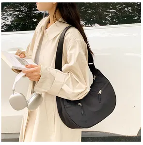 Detail of black nylon crescent bag featuring functional double zippers and adjustable strap