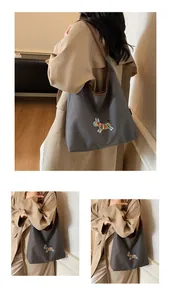 Close-up of zebra embroidery and premium leather trim on a gray canvas hobo bag