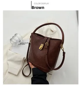 Detail of brown vintage leather bucket bag featuring gold metal twist lock and handle
