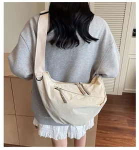 Detail of beige nylon half-moon crossbody bag with woven zipper puller and wide strap