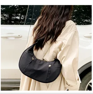 Detail of a black nylon crescent bag with metal zippers shown in a lifestyle street shot