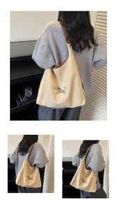 Detail of beige canvas hobo bag featuring colorful zebra embroidery and brown leather trim