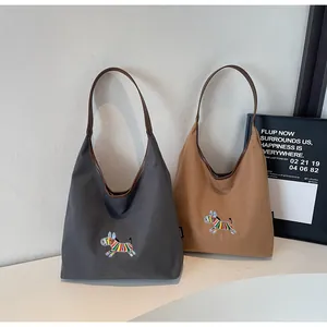 Detailed embroidery of rainbow zebra on canvas tote bag with brown leather handles